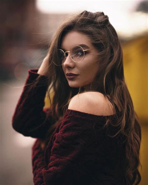 A Woman Wearing Glasses Is Posing For The Camera With Her Hand On Her