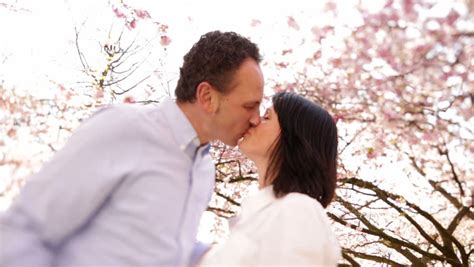 Mature Couple Standing Under Cherry Tree First Looking At