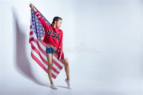Asian Girl In Red Sweatshirt With Usa Word Posing With American Flag