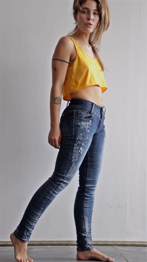 a woman in yellow shirt and jeans posing for the camera