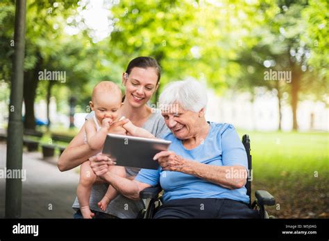 Grandmother Daughter And Granddaughter Having Fun With Tablet In A Park