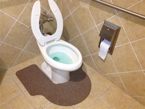 white toilet sitting    paper dispenser   tiled floor