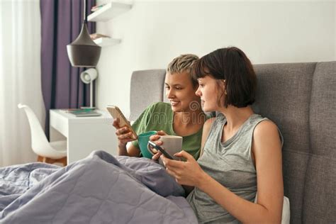 Lesbians With Tea Using Smartphones On Bed At Home Stock Image Image