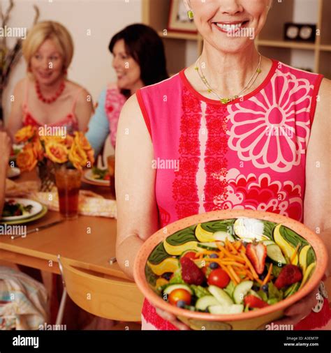 Portrait Of A Mature Woman Holding A Bowl Of Salad And Her Friends
