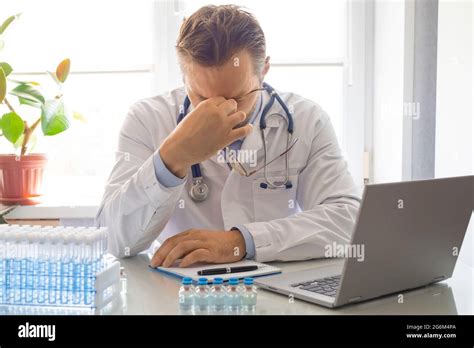 Photo Of A Tired Doctor He Takes Off His Glasses And Rubs The Bridge
