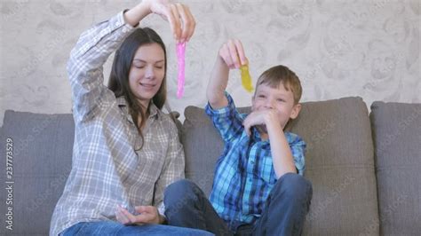 Happy Mom And Son Are Playing With Slime Sitting On The Sofa