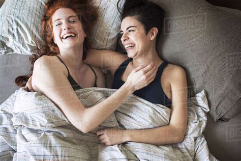 High Angle View Of Cheerful Lesbians Relaxing On Bed