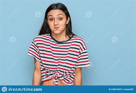 Young Hispanic Girl Wearing Casual Clothes Puffing Cheeks With Funny
