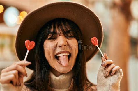 Brunette Woman Wearing Winter Hat Being Funny Holding Lollipops