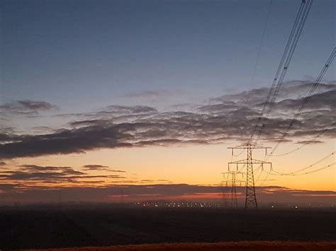 sun  setting  power lines   open field  clouds  blue sky