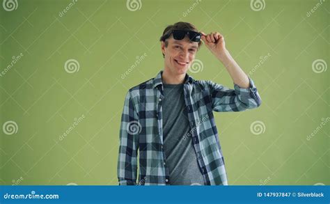 Portrait Of Cool Young Man Taking Off Sunglasses And Smiling Looking At