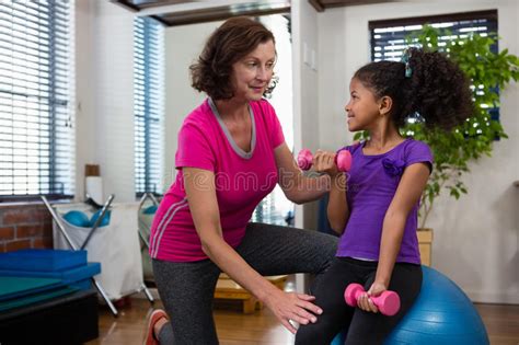 Female Physiotherapist Helping Girl Patient In Performing Exercise With