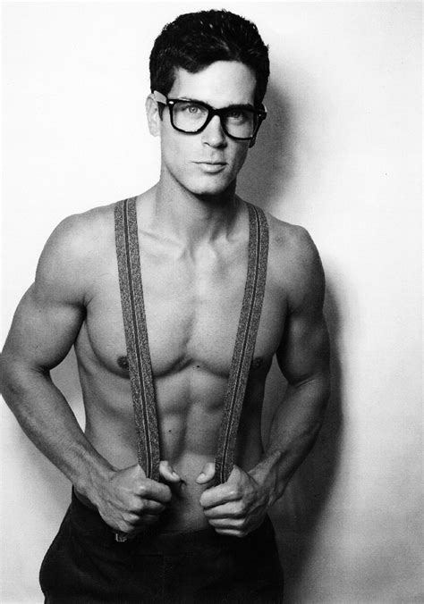 a shirtless man wearing glasses and suspenders