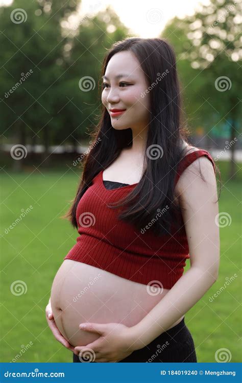Belly Close Up Asian Pregnant Woman In Garden Forest Lawn Outdoor
