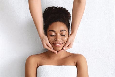 Therapist Making Lifting Facial Massage For Beautiful Black Lady Stock