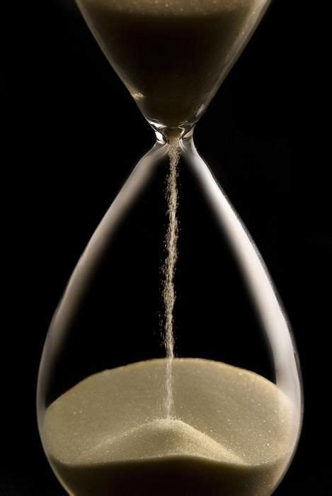 An Hourglass With Sand Coming Out Of The Top And Bottom In Front Of A