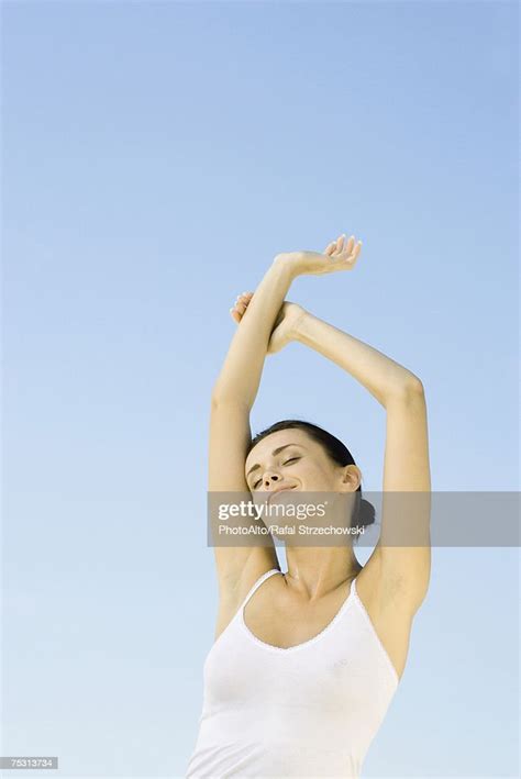 woman stretching arms overhead sky in background low angle view photo