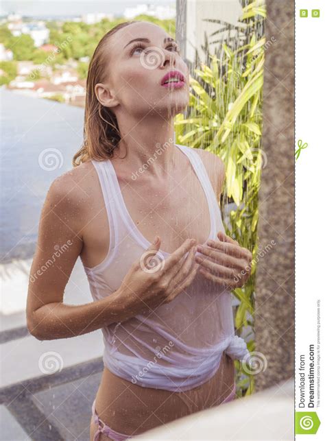 seksowna kobieta w bikini i białym podkoszulku bez rękawów bierze outdoors prysznic na dachu