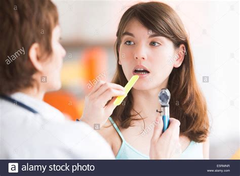 Female Doctor Using A Tongue Depressor To Allow An