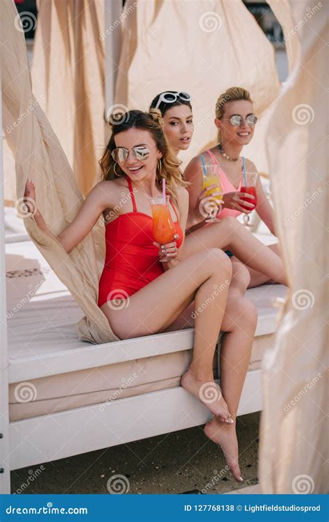 Happy Girlfriends In Swimwear And Sunglasses Drinking Cocktails In