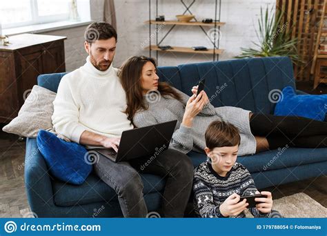 Mother Father And Son Using Laptop And Mobile Phones At