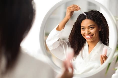 Premium Photo Smiling Black Woman Applying Serum For Hair Repair