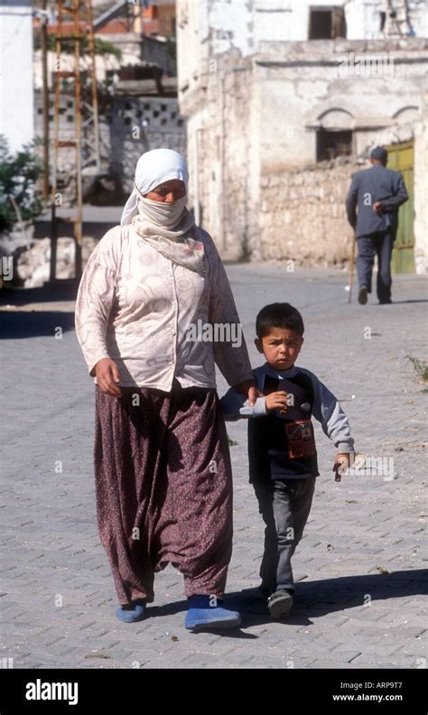 turkish mother and son walking through a village street in turkey stock