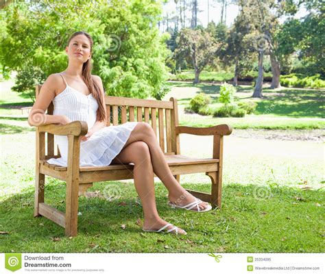Woman With Her Legs Crossed Sitting On A Bench Royalty