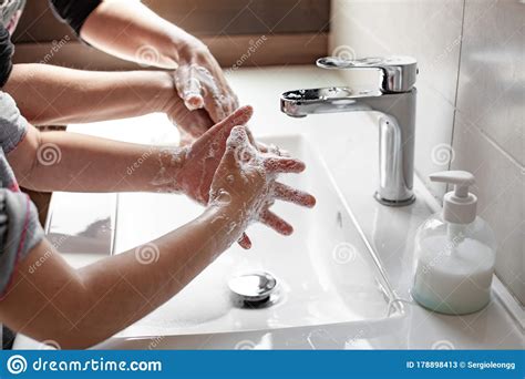 Mother Teaching Her Daughter How To Properly Wash Their Hands With Soap