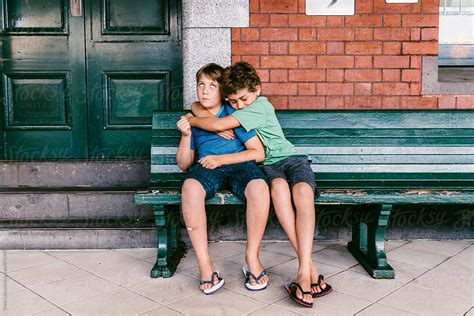 boy hugging   annoyed sitting  bench  stocksy