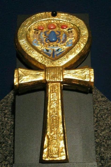 an ornate gold cross on top of a granite block in front of a dark blue sky