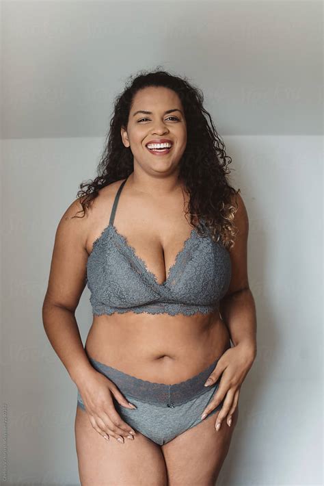a beautiful plus size woman in her twenties lounging at home in a bra