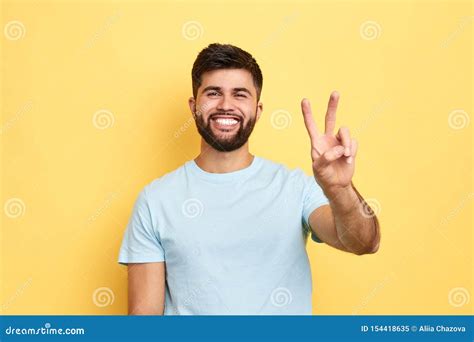 smiling cheerful young man showing  fingers  victory sign stock