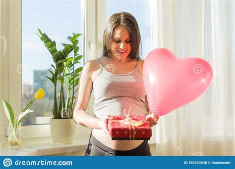 happy pregnant female with valentines t box and red heart balloon