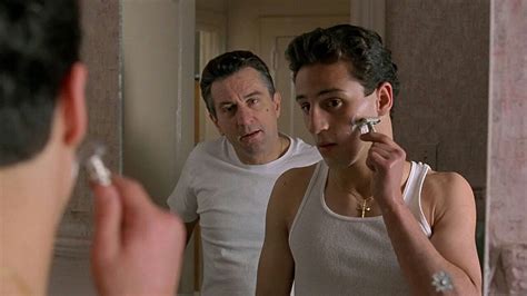 A Man Brushing His Teeth In Front Of A Mirror With Another Man Looking