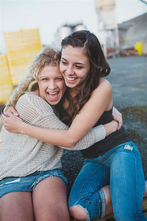 two pretty teenage girls hugging together outside saying goodbye
