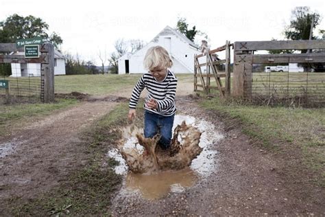 image  young boy splashing  muddy puddle   farm austockphoto