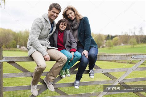 portrait  boy sitting  parents  wooden fence  countryside