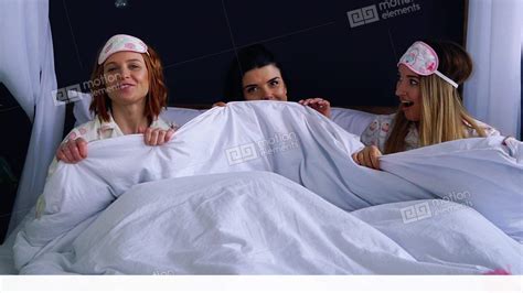 Three Girls Mess Under A Blanket In Pajamas Get Out Of Bed Smiling And
