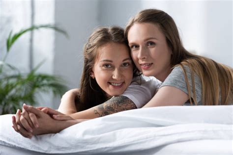Two Smiling Lesbians Holding Hands While Sitting Sofa