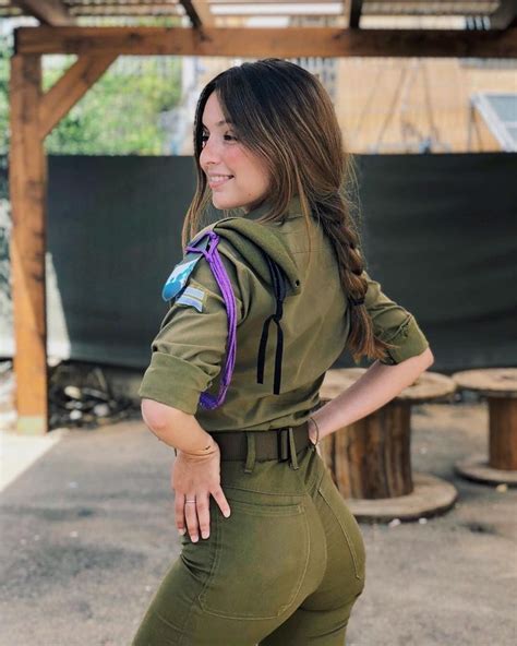 A Woman In Army Green Jumpsuits Posing For The Camera With Her Hands On