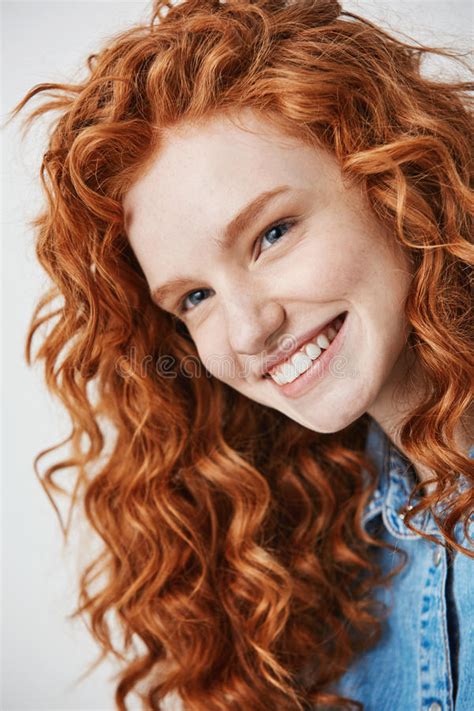 close up of redhead beautiful girl with freckles smiling looking at camera over white background