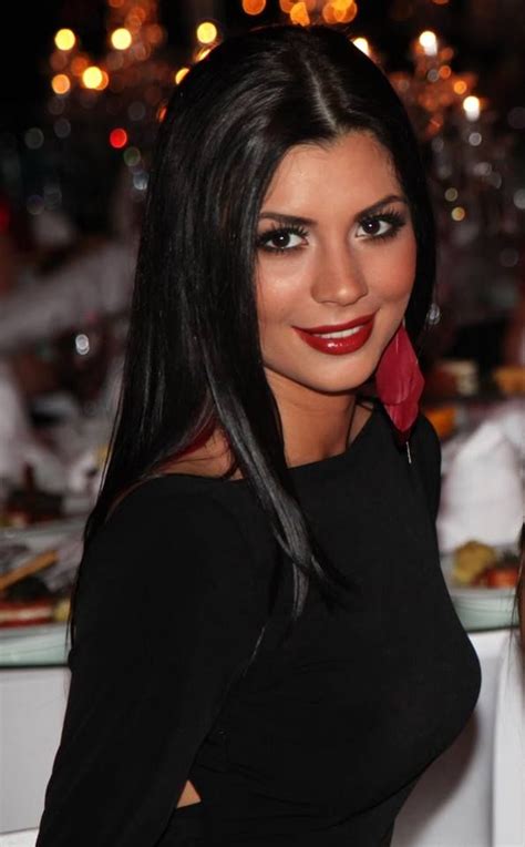 A Woman With Long Black Hair And Red Lipstick Posing For The Camera At