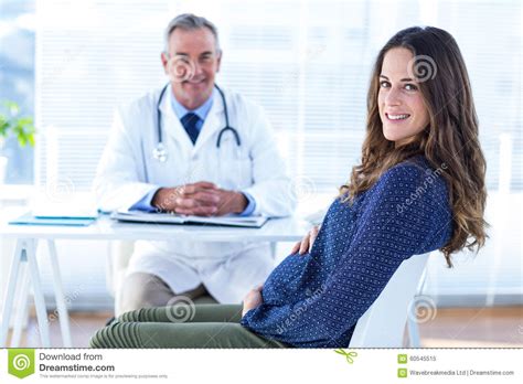 Portrait Of Pregnant Woman With Male Doctor In Clinic Stock Image