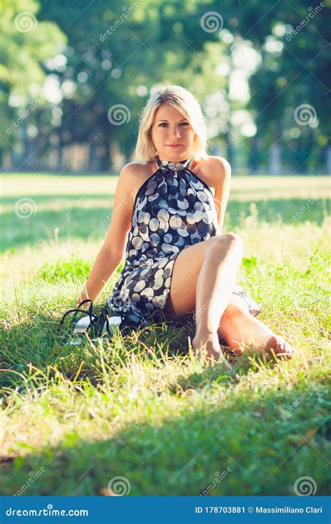 Portrait Of Fashionable Young Sensual Blonde Woman In Garden Sitting On