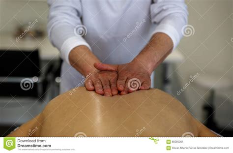 a masseuse applies his hands on the back of a patient