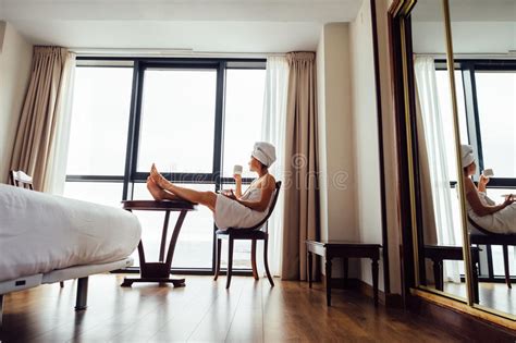 woman relaxes with cup of tea near the panorama window in luxury stock