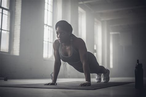 black woman doing push ups in dark gym photo by gable denims black