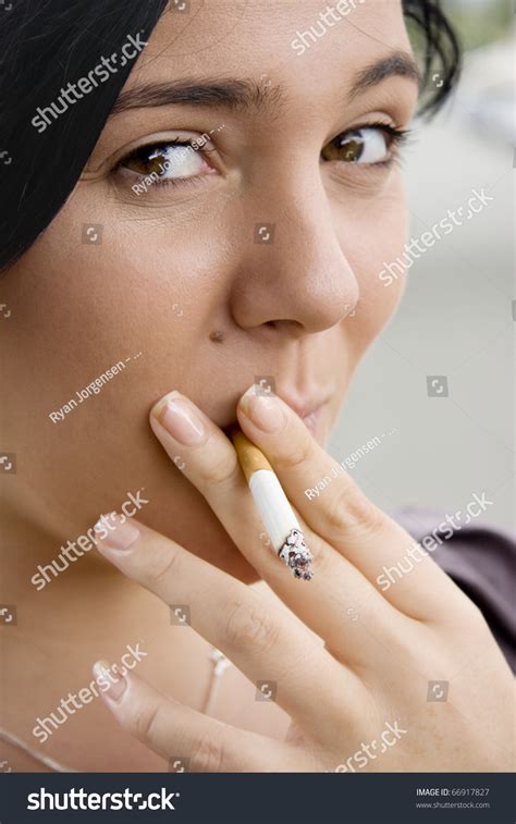 Young Woman Inhaling Smoke From A Lit Cigarette With A Mischievous Look