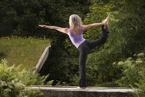 mature woman practicing yoga dancer pose  garden stock photo